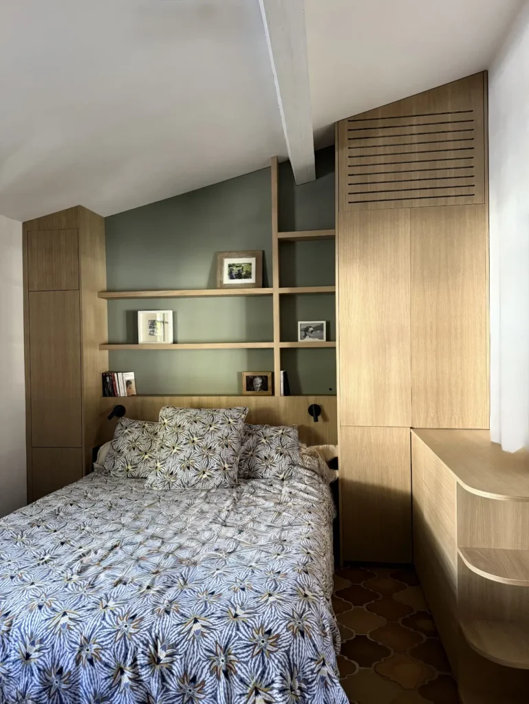 Agencement de chambre sous pente avec dressing encastré, pont de lit et étagères sur-mesure en bois dans le Var.